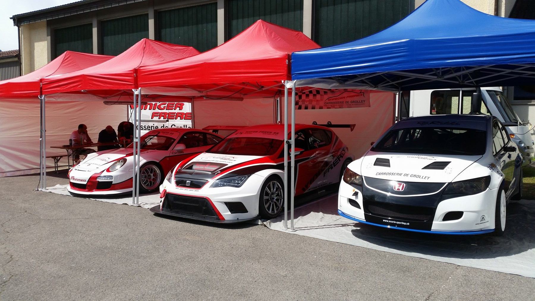 Stands de course aux couleurs Winiger avec voitures de compétition